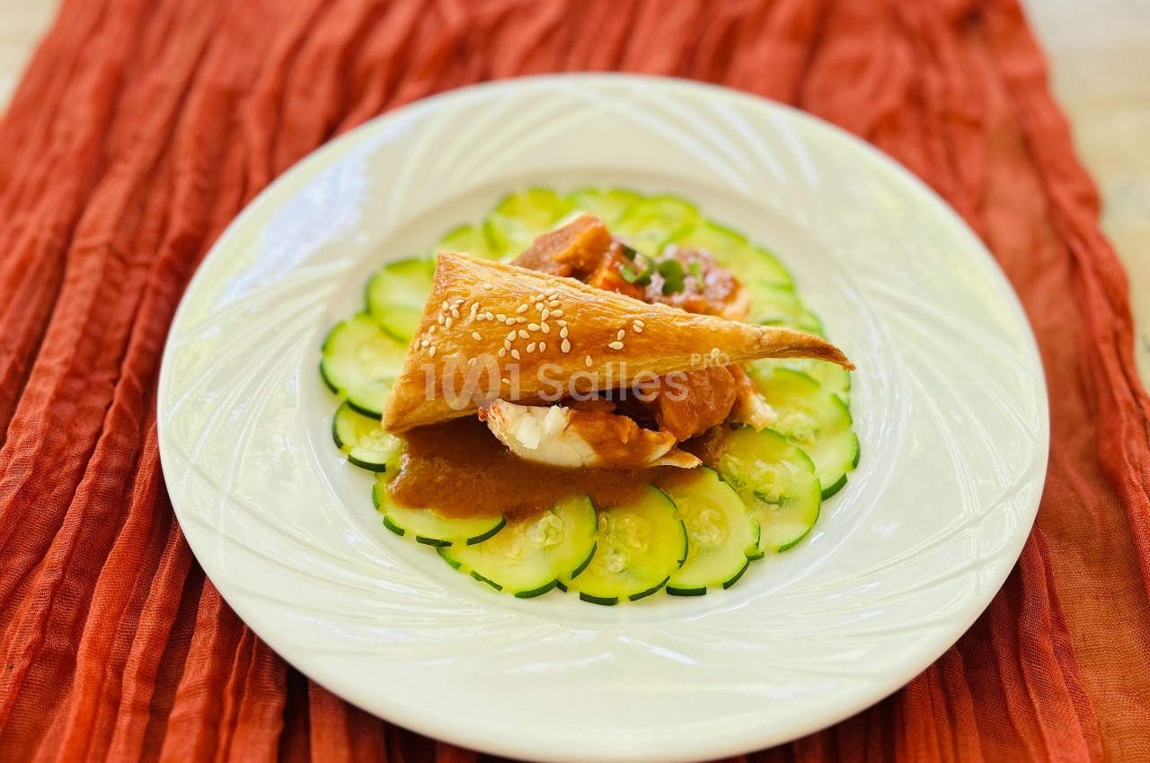 Assiette garnie de tranches de concombre disposées en cercle, surmontées de pâte feuilletée et d'une garniture en sauce.