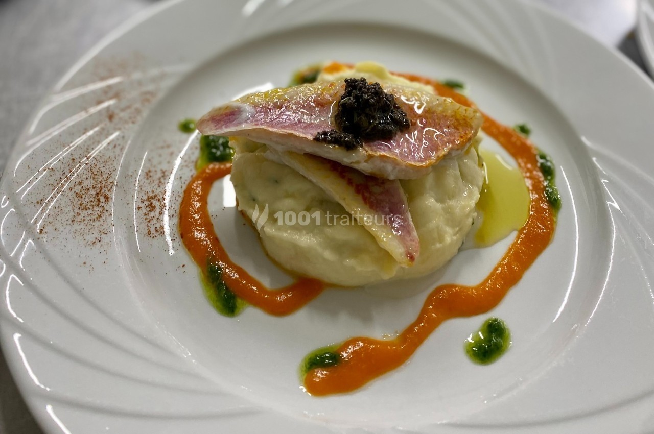 Filet de poisson sur purée, décoré de sauce rouge et verte, avec une touche de condiment sombre au centre.