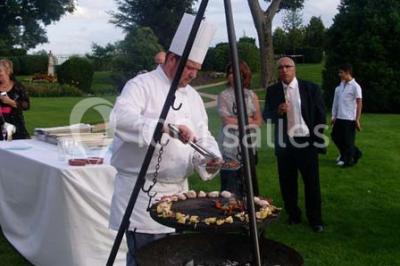 Miniature Traiteur Garancières (Yvelines) - Havane Traiteur #20 Table dressée avec nappes blanches, couverts, menus et bouquets de fleurs, entourée de chaises en bois dans une salle.