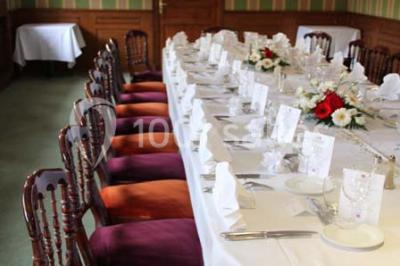 Miniature Traiteur Garancières (Yvelines) - Havane Traiteur #23 Table dressée avec nappes blanches, couverts, menus et bouquets de fleurs, entourée de chaises en bois dans une salle.