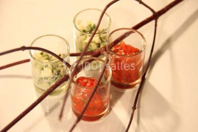 Table dressée avec nappes blanches, couverts, menus et bouquets de fleurs, entourée de chaises en bois dans une salle.