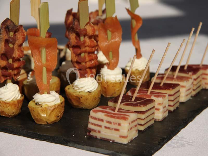 Plateau d'amuse-bouches comprenant brochettes de bacon, pommes de terre garnies et cubes de fromage en couches.