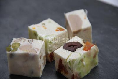 Table dressée avec nappes blanches, couverts, menus et bouquets de fleurs, entourée de chaises en bois dans une salle.