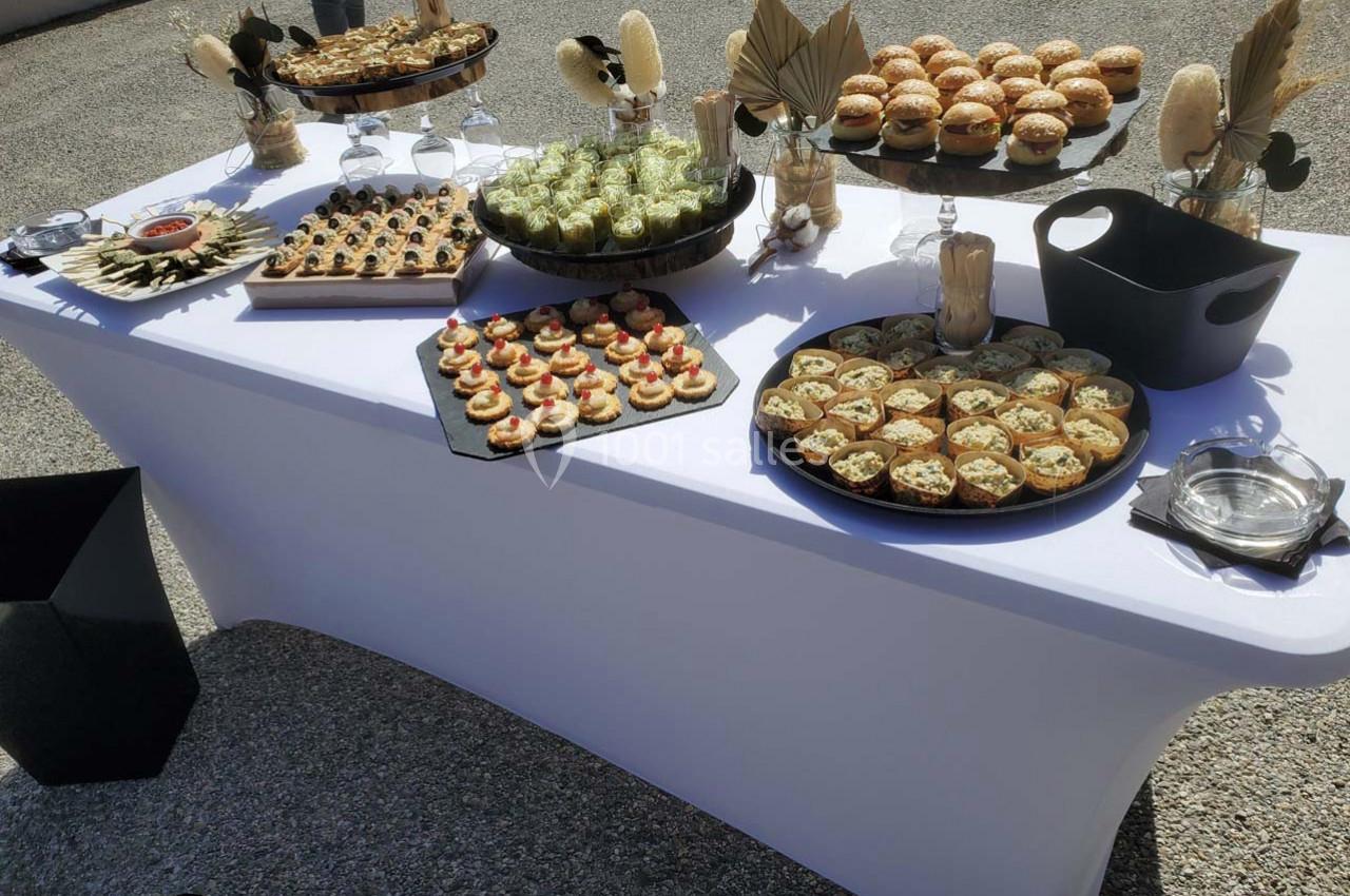 Buffet en extérieur avec une table dressée de bouchées salées variées, présentées sur des plateaux élégants.