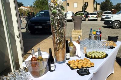 Miniature Traiteur Robion (Vaucluse) - Dupas Traiteur #4 Un serveur remplit un verre de boisson pour un homme lors d'un buffet avec des verrines et des invités en arrière-plan.