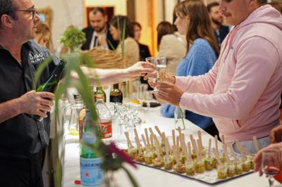 Miniature Traiteur Robion (Vaucluse) - Dupas Traiteur #13 Un serveur remplit un verre de boisson pour un homme lors d'un buffet avec des verrines et des invités en arrière-plan.