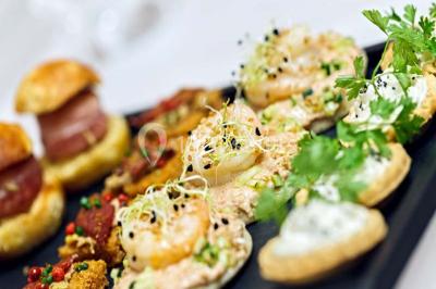 Miniature Traiteur Chaponost (Rhône) - Jacques Lafargue Traiteur #12 Une main coupe un rouleau de foie gras sur une planche en bois, entouré de figues et de tomates cerises.