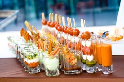 Miniature Traiteur Chaponost (Rhône) - Jacques Lafargue Traiteur #18 Une main coupe un rouleau de foie gras sur une planche en bois, entouré de figues et de tomates cerises.