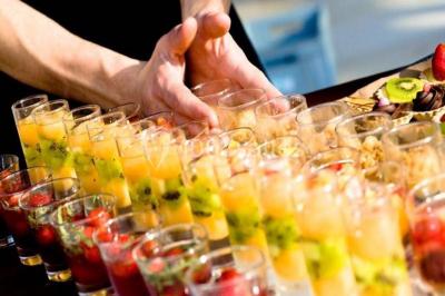 Miniature Traiteur Chaponost (Rhône) - Jacques Lafargue Traiteur #22 Une main coupe un rouleau de foie gras sur une planche en bois, entouré de figues et de tomates cerises.