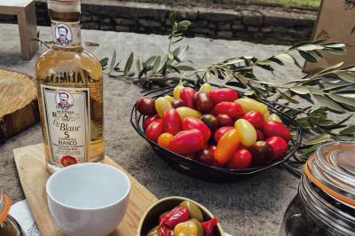 Miniature Traiteur Chaponost (Rhône) - Jacques Lafargue Traiteur #3 Une main coupe un rouleau de foie gras sur une planche en bois, entouré de figues et de tomates cerises.