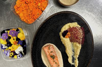 Miniature Traiteur Chaponost (Rhône) - Jacques Lafargue Traiteur #23 Une main coupe un rouleau de foie gras sur une planche en bois, entouré de figues et de tomates cerises.