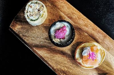 Miniature Traiteur Chaponost (Rhône) - Jacques Lafargue Traiteur #30 Une main coupe un rouleau de foie gras sur une planche en bois, entouré de figues et de tomates cerises.