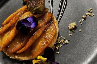 Miniature Traiteur Chaponost (Rhône) - Jacques Lafargue Traiteur #33 Une main coupe un rouleau de foie gras sur une planche en bois, entouré de figues et de tomates cerises.