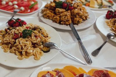 Une main coupe un rouleau de foie gras sur une planche en bois, entouré de figues et de tomates cerises.