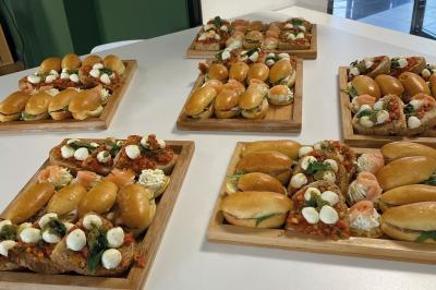 Une main coupe un rouleau de foie gras sur une planche en bois, entouré de figues et de tomates cerises.