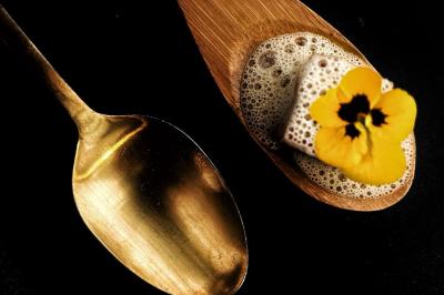 Une main coupe un rouleau de foie gras sur une planche en bois, entouré de figues et de tomates cerises.