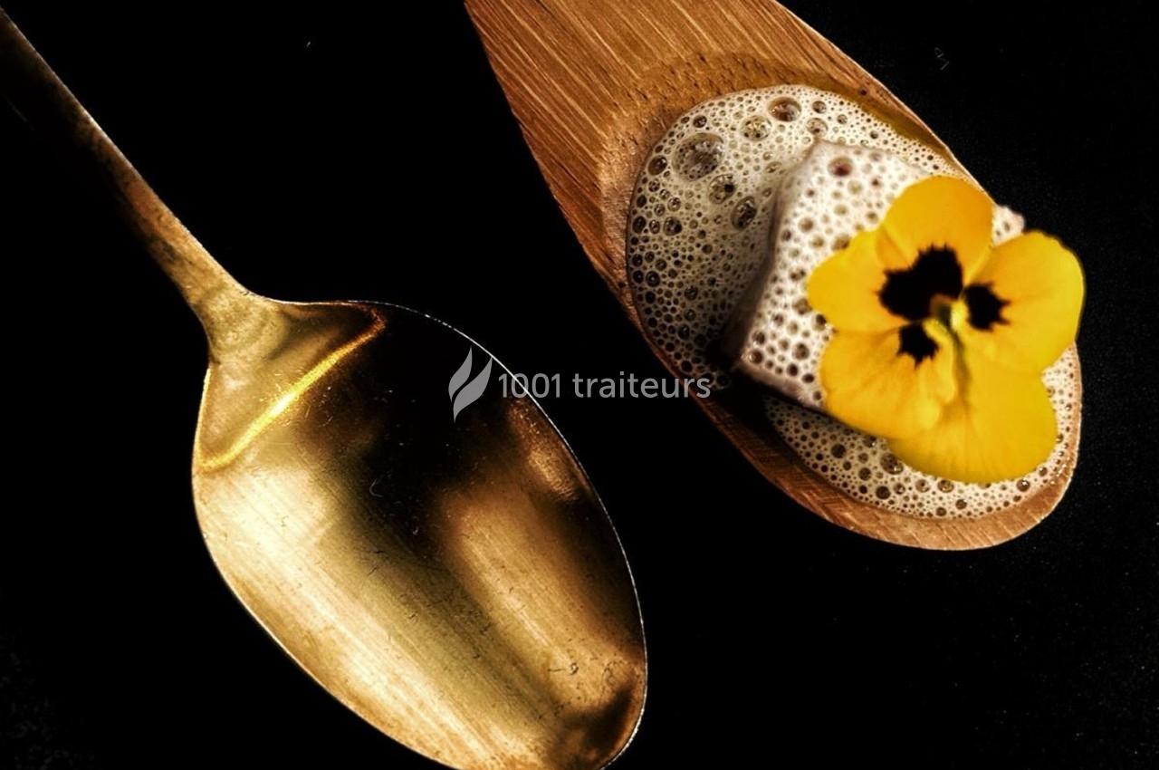 Cuillère dorée à côté d'une cuillère en bois contenant une mousse, un cube et une fleur jaune.