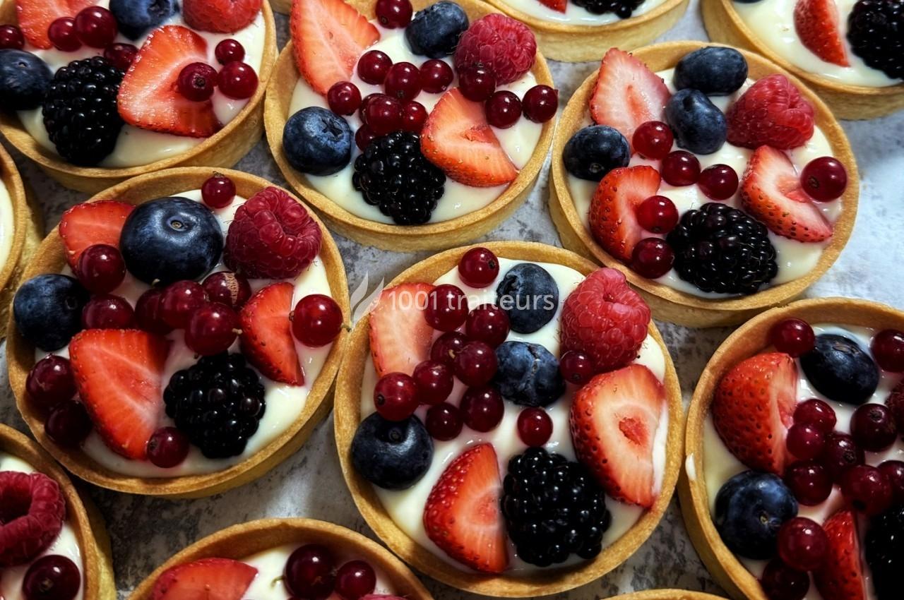 Tartelettes garnies de crème et décorées de fruits rouges et bleus comme fraises, myrtilles, mûres et groseilles.