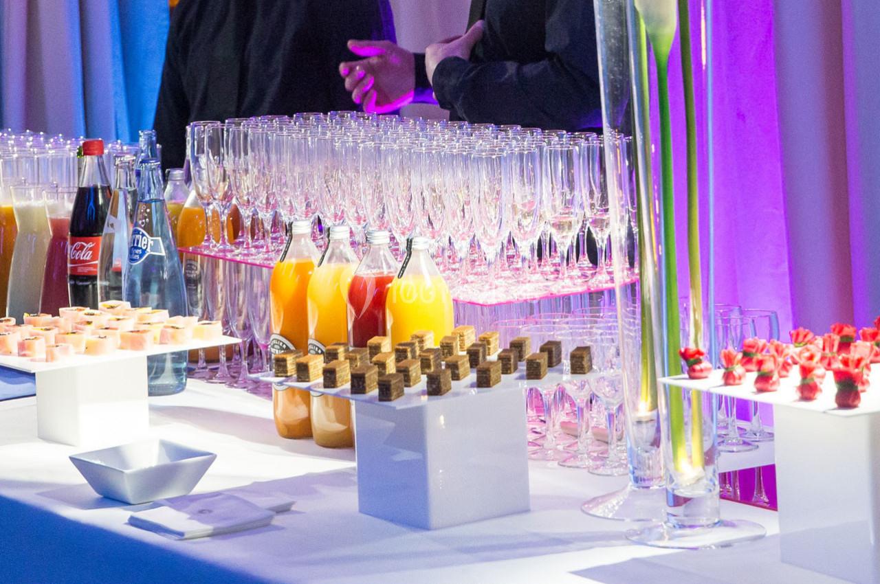 Table de buffet avec verrines, jus de fruits, bouteilles, flûtes à champagne et décorations florales.