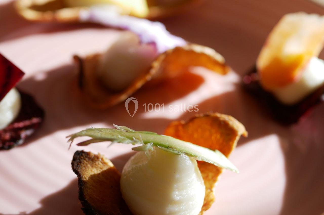 Chips de légumes garnies de purée et décorées de fines tranches de légumes sur une assiette rose.