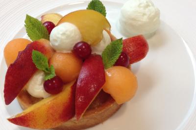 Tarte garnie de fruits frais variés, crème chantilly et feuilles de menthe, servie sur une assiette blanche.