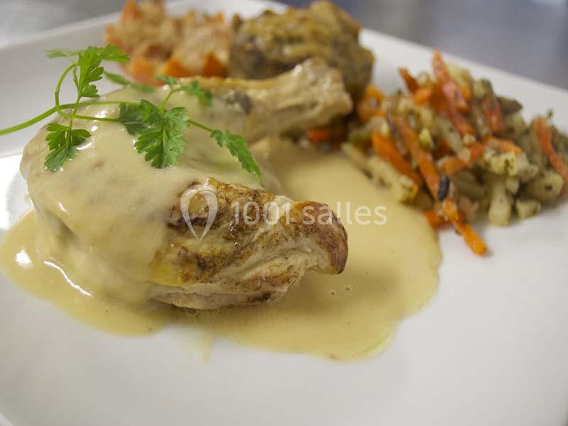 Assiette de volaille nappée de sauce, accompagnée de légumes sautés et d'un gratin en arrière-plan.