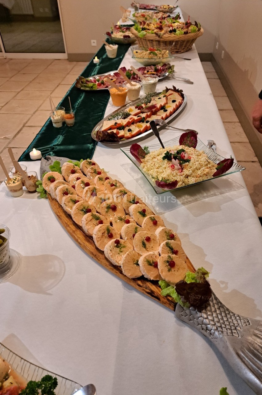 Buffet composé de plats variés, notamment des rouleaux de poisson, salades et desserts, présenté sur une grande table.