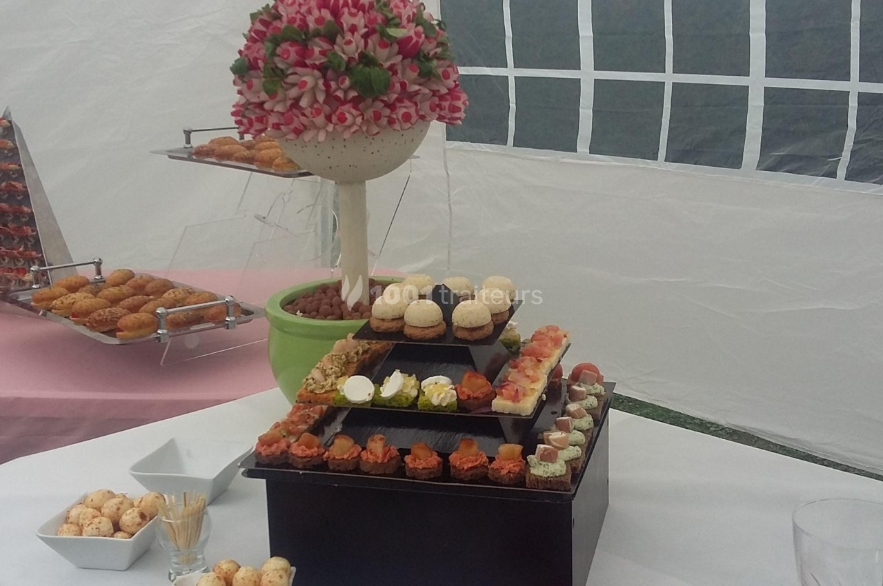 Plateau de mignardises variées avec macarons et amuse-bouches, disposé sur une table dans une tente de réception.