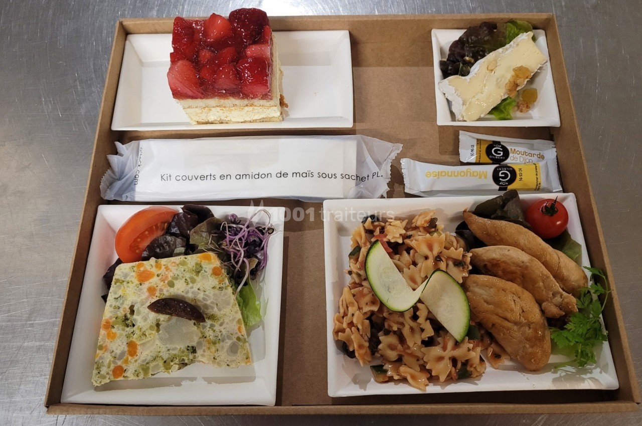 Plateau-repas avec salade de pâtes, terrine de légumes, fromage, dessert aux fraises et couverts emballés.