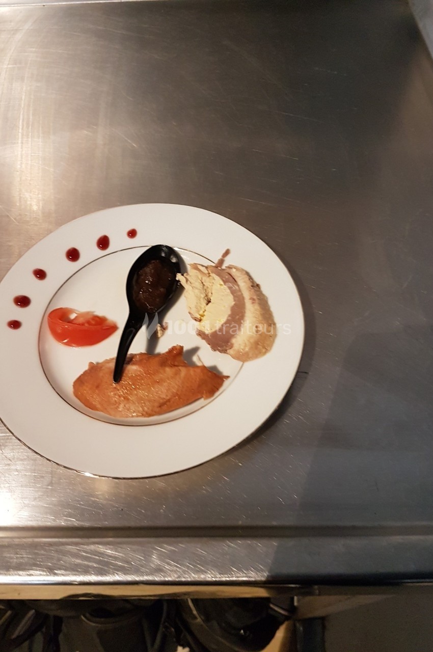Assiette contenant une présentation gastronomique avec viande, purée, sauce au chocolat et décoration de tomate et coulis.
