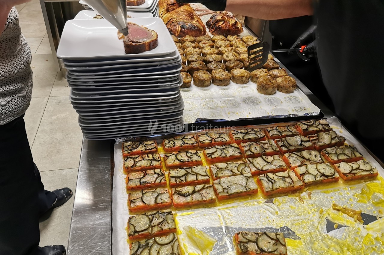 Préparation de plats en cuisine, avec des assiettes empilées, des feuilletés aux légumes et des champignons farcis.