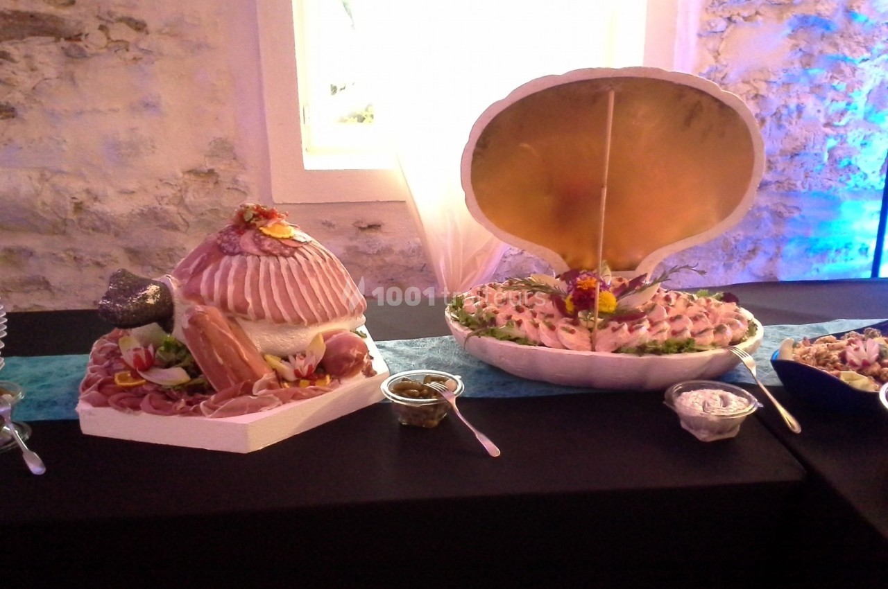 Plateaux de fruits de mer et charcuterie présentés dans des coquilles géantes sur une table de réception.