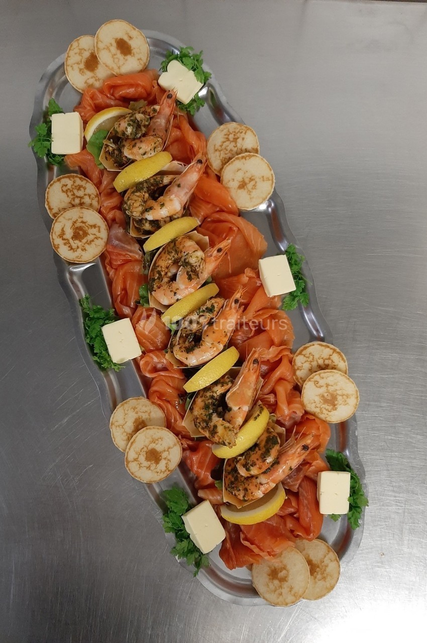 Plateau de saumon fumé, crevettes, blinis, beurre et citron, présenté sur un plat argenté avec garniture verte.