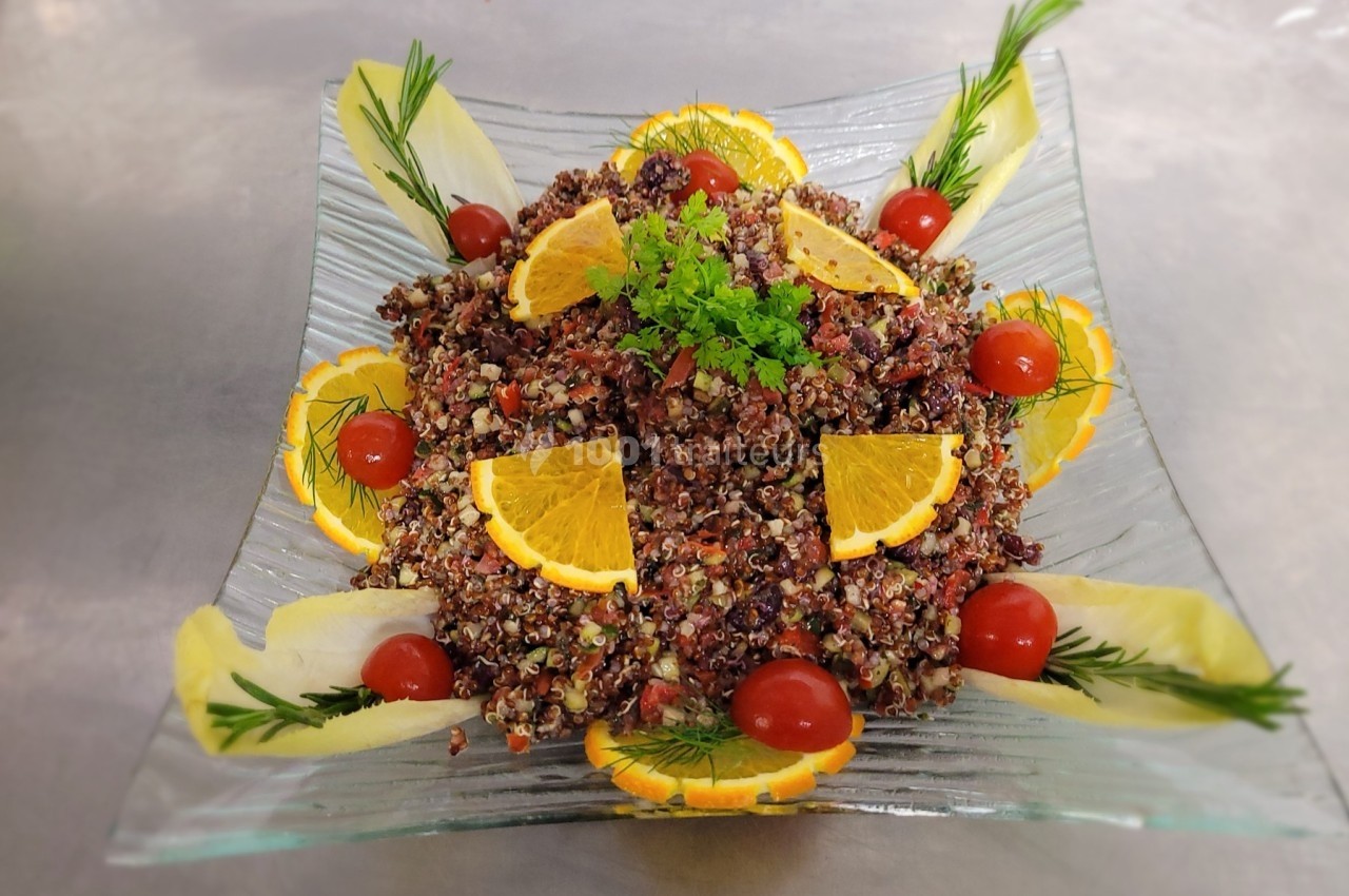 Salade de quinoa colorée garnie de tranches d'orange, tomates cerises, herbes fraîches et feuilles d'endive.