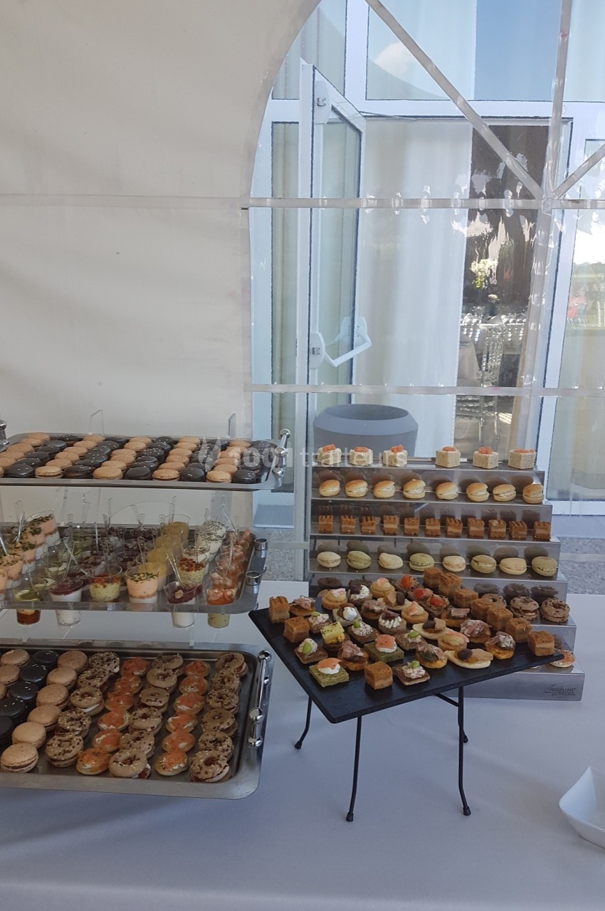 Buffet de petits fours variés disposés sur des plateaux dans un cadre lumineux avec une grande baie vitrée.