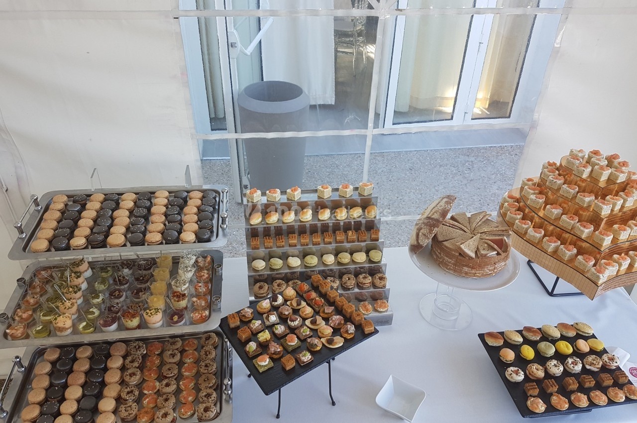 Buffet de desserts variés comprenant macarons, verrines, tartes et gâteaux, présenté sur des plateaux et supports.