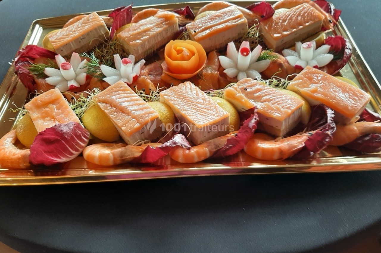 Plateau de saumon fumé avec crevettes, tranches de citron, fleurs sculptées et décoration de feuilles rouges.