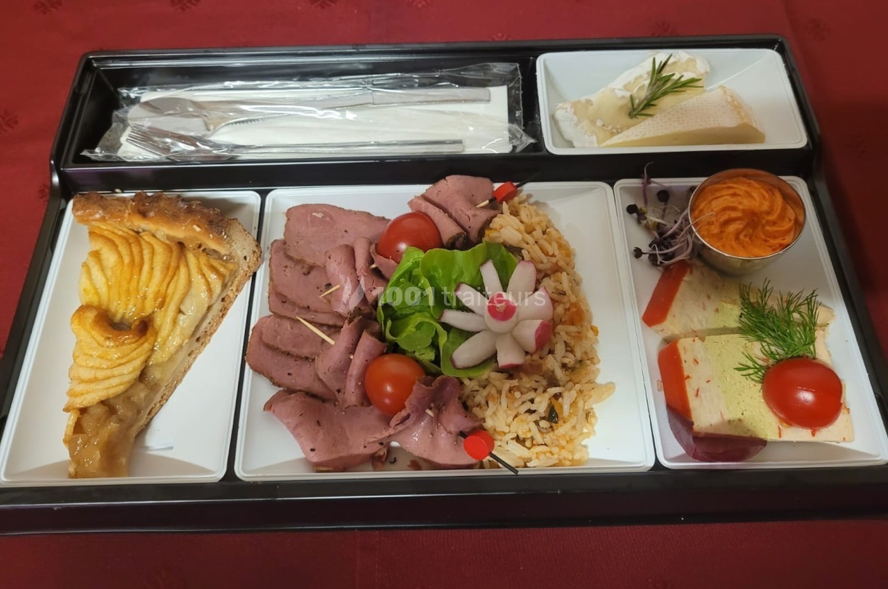 Plateau-repas composé de rôti de bœuf, riz, crudités, tarte aux pommes, fromage, mousse et couverts sur une nappe rouge.