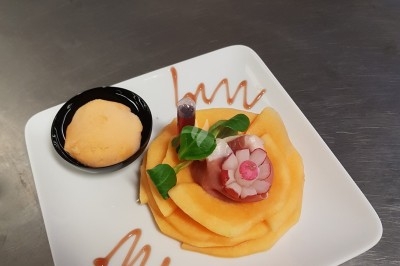 Assiette composée de foie gras, gelée, pain brioché, tranches d'orange, groseilles, jeunes pousses et graines noires.