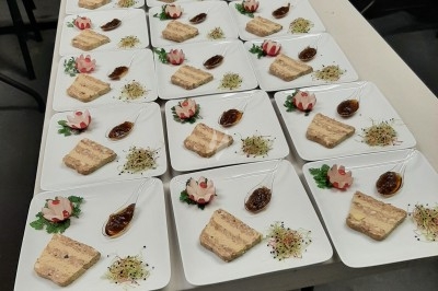 Assiette composée de foie gras, gelée, pain brioché, tranches d'orange, groseilles, jeunes pousses et graines noires.