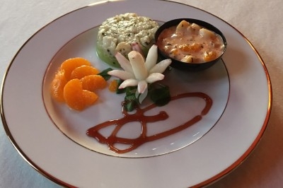 Assiette composée de foie gras, gelée, pain brioché, tranches d'orange, groseilles, jeunes pousses et graines noires.