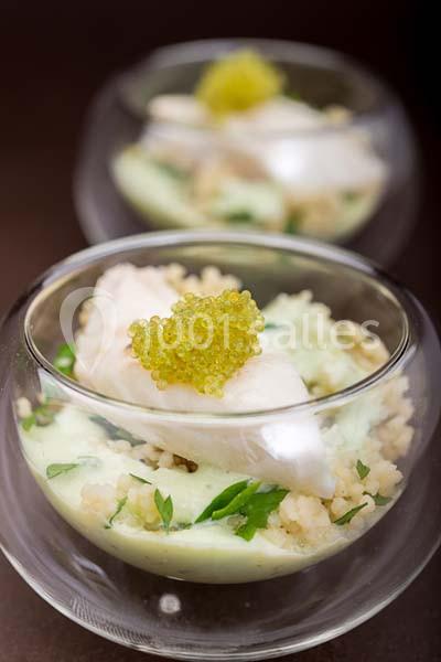 Verrines contenant un plat raffiné à base de poisson, perles de caviar, sauce verte et céréales.