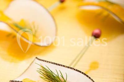 Dessert au chocolat brillant orné de feuille d'or, posé sur une base avec éclats de cacao, sur fond sombre.