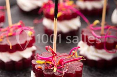 Dessert au chocolat brillant orné de feuille d'or, posé sur une base avec éclats de cacao, sur fond sombre.