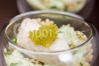 Dessert au chocolat brillant orné de feuille d'or, posé sur une base avec éclats de cacao, sur fond sombre.