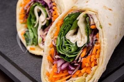 Dessert au chocolat brillant orné de feuille d'or, posé sur une base avec éclats de cacao, sur fond sombre.