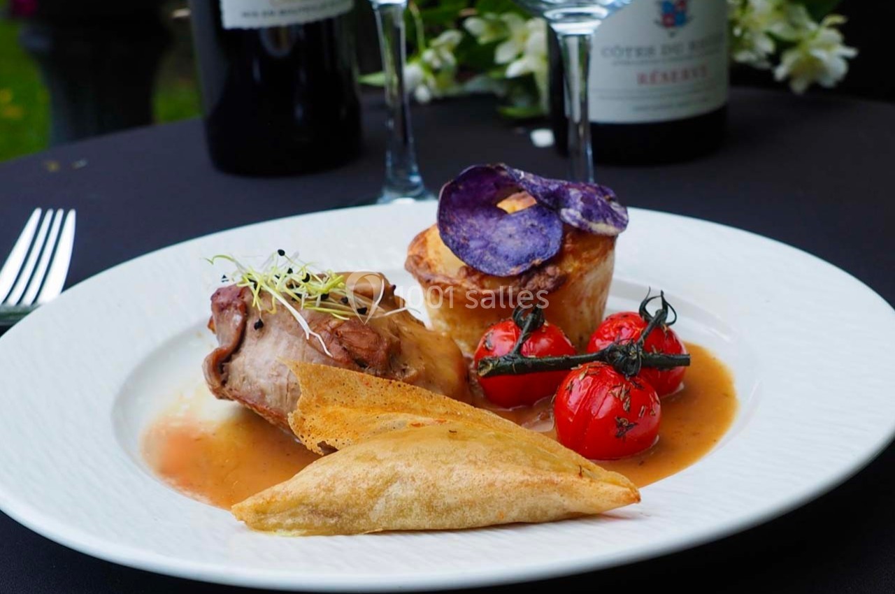 Assiette gastronomique avec viande en sauce, légumes grillés, chips violettes et croustillant, servie sur une table élégante.