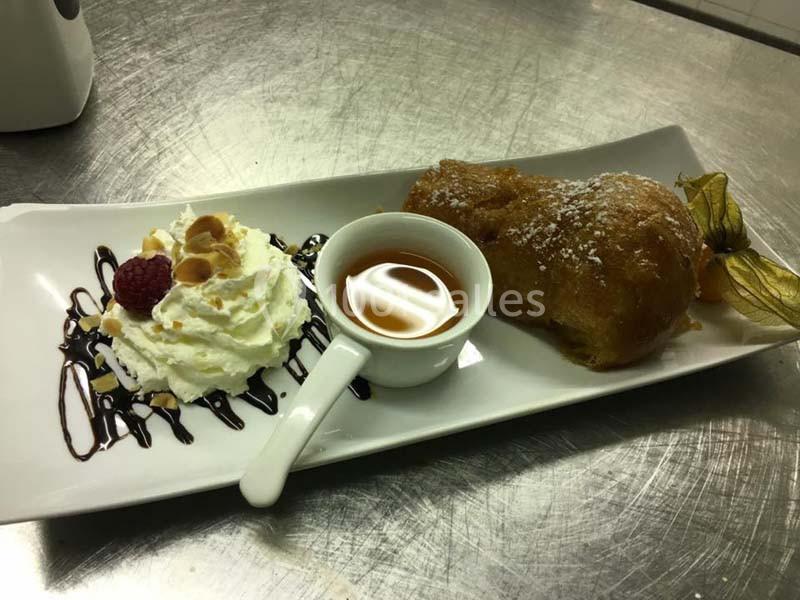 Dessert composé d'une chouquette, d'une sauce caramel, de chantilly décorée de chocolat, d'amandes et d'une framboise.