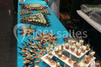 Table décorée pour un dîner, avec nappes blanches, serviettes pliées, lanternes, fleurs et couverts disposés.