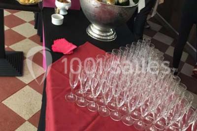 Table décorée pour un dîner, avec nappes blanches, serviettes pliées, lanternes, fleurs et couverts disposés.